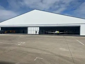 Aircraft hanger with 2 hangar doors open and an aeroplane exiting